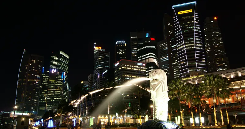 The Merlion fountain at Merlion Park at night, with the Singapore skyline lit behind it
