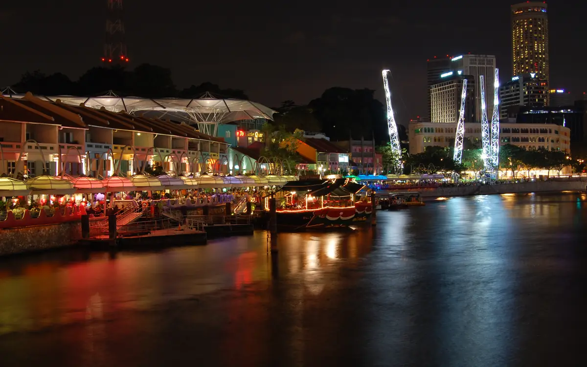 Clarke Quay on the Singapore River after dark, with lit restaurants and boats along the water