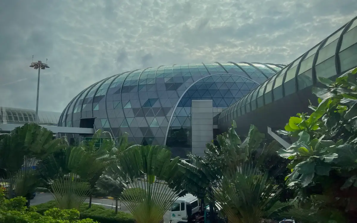 The exterior of Changi Airport under an overcast sky, with the terminal building and its covered forecourt