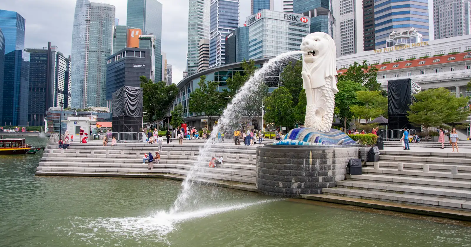 The Merlion statue at Merlion Park, water spilling from its mouth into the bay, with the Marina Bay skyline behind it